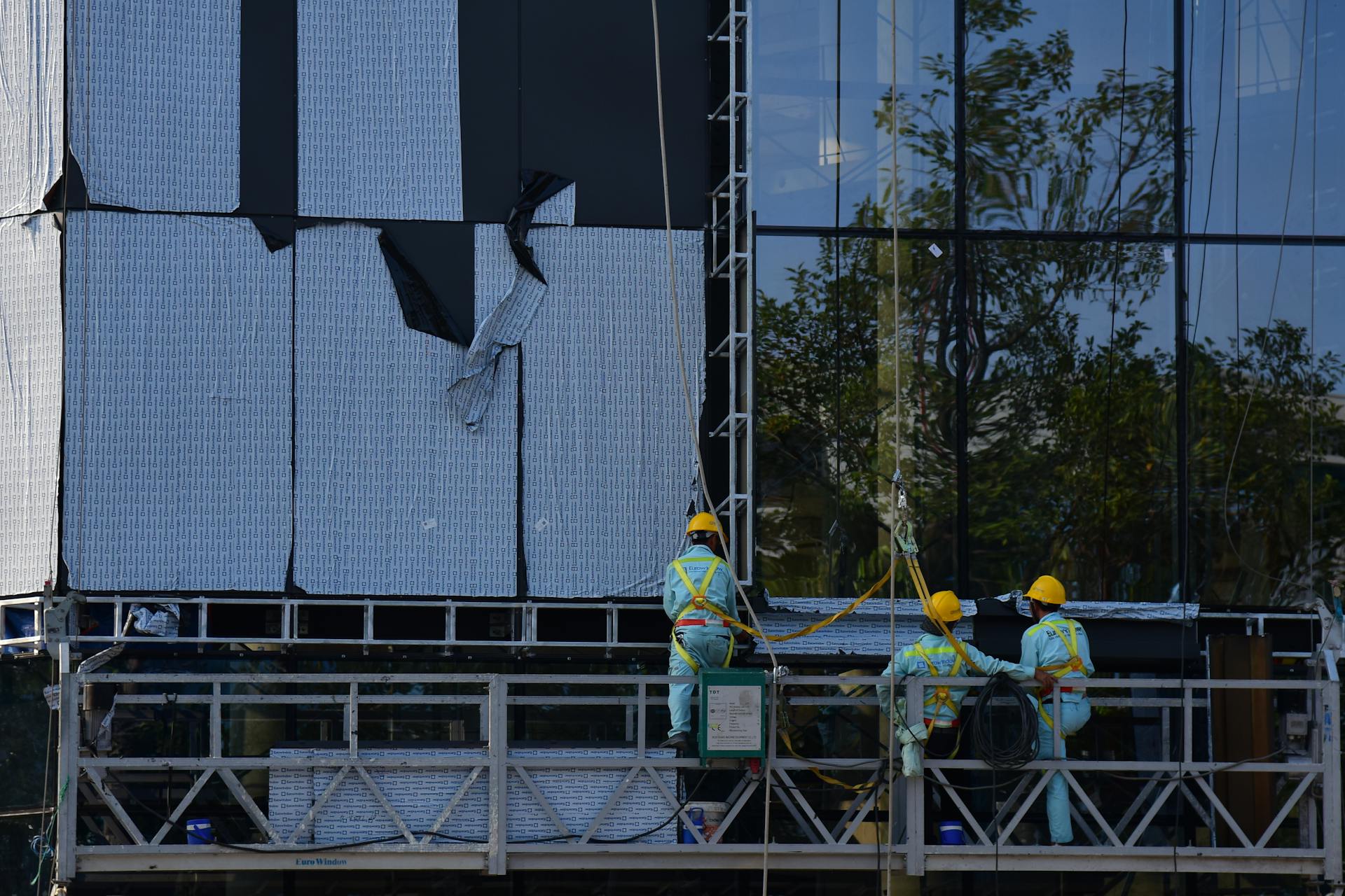 Suspended swing stage scaffolding on a high-rise building for glazing work